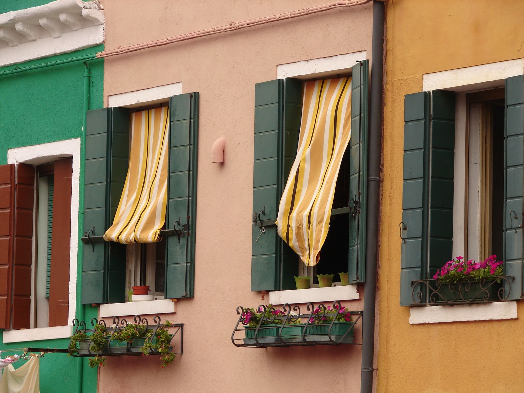 A colorful building facade with striped awnings and flower boxes in the windows